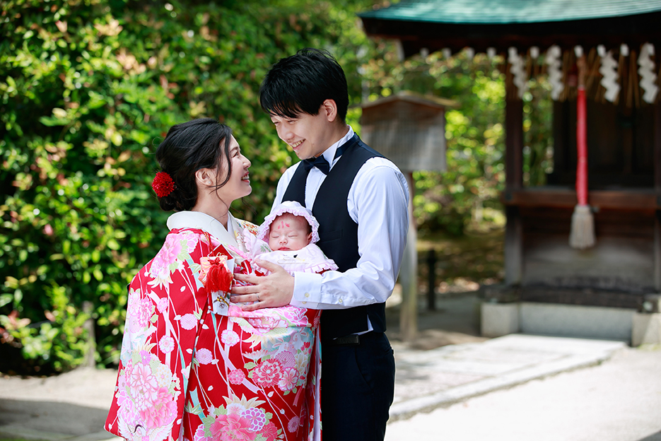 京都のわら天神ロケーション撮影でお宮参りの着物を着て赤ちゃんを抱っこしたママがパパと顔を見合わせ幸せな雰囲気
